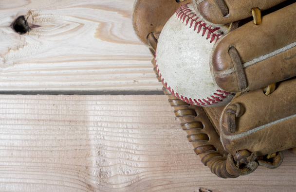 Régi kopott bőr baseball-kesztyű és használt labda egy fából készült asztal  - Fotó, kép