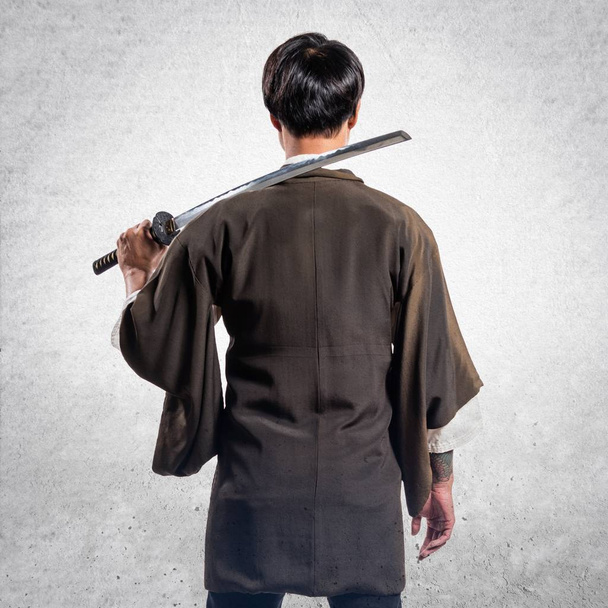 Азиатский самурай с катаной на текстурированном фоне
 - Фото, изображение