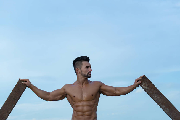 man with muscular body training at rusty iron rod - Zdjęcie, obraz