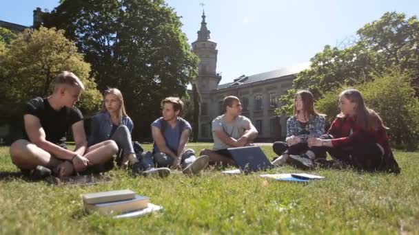 Groep studenten chatten op het gazon van de campus - Video
