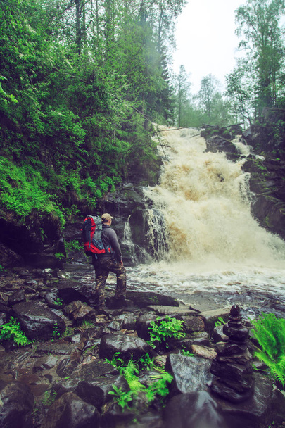 Hiker with a backpack near waterfall. - Fotoğraf, Görsel