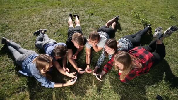 Bovenaanzicht tieners in cirkel met behulp van telefoons in park - Video