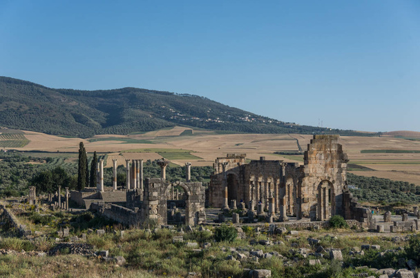 Θέα στην Βασιλική και το ναό του Καπιτωλίου, αρχαιολογικό χώρο της Volubilis, αρχαία Ρωμαϊκή Αυτοκρατορία πόλη, μνημείο παγκόσμιας κληρονομιάς της UNESCO, βρίσκεται στο Μαρόκο κοντά σε Μεκνές - Φωτογραφία, εικόνα
