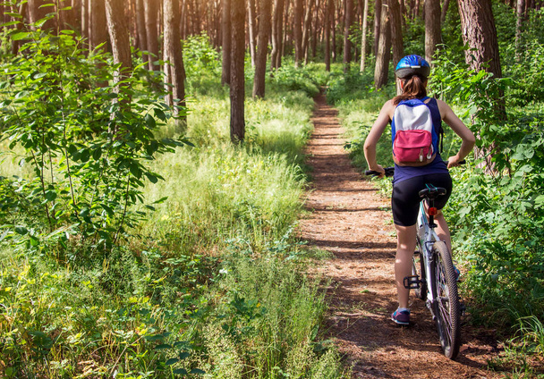 mujer joven montando en bicicleta en el bosque - Foto, imagen