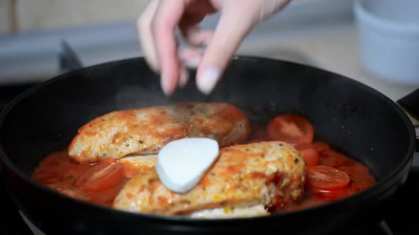 Žena vařit kuře v rajčatové omáčce. Dejte kousky mozzarelly na kuře - Záběry, video
