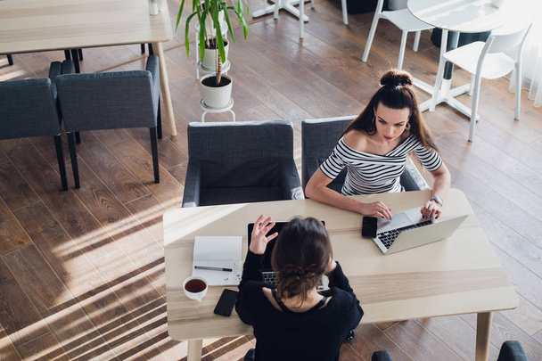 Overhead shot of business women working in a cafe. Two business partners sitting at the desk in office and interacting. - Photo, Image