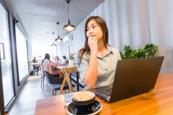 Les femmes d'affaires attrayantes utilisent un ordinateur portable avec une boisson au café latte, les entreprises indépendantes
 - Photo, image
