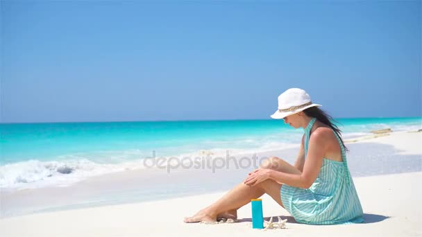 Молодая женщина наносит крем на гладкие загорелые ноги на тропическом пляже
 - Кадры, видео