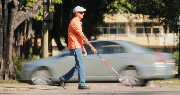 Сліпа людина перетинає дорогу з автомобілями і трафіком
 - Фото, зображення