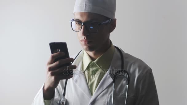 El médico utiliza un teléfono inteligente. Trabajador médico navegando por Internet usando un teléfono móvil
. - Imágenes, Vídeo