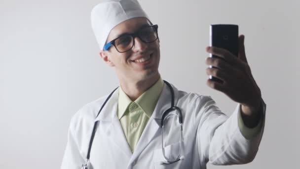 Doktor bir smartphone kullanarak bir selfie yapıyor. Tıbbi işçi kendisi fotoğraf arşivi. - Video, Çekim
