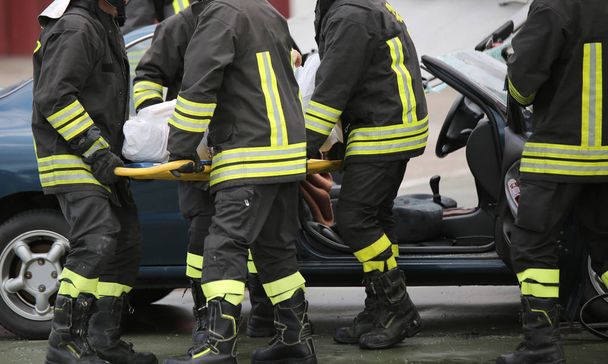 Quatro bravos bombeiros transportam os feridos com uma maca
 - Foto, Imagem