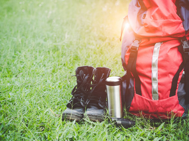 Hiking travel gear on glasses. Items include hiking boots, cup, map,binoculars. Flat lay of outdoor travel equipment items for mountain camping trip.  - Photo, image