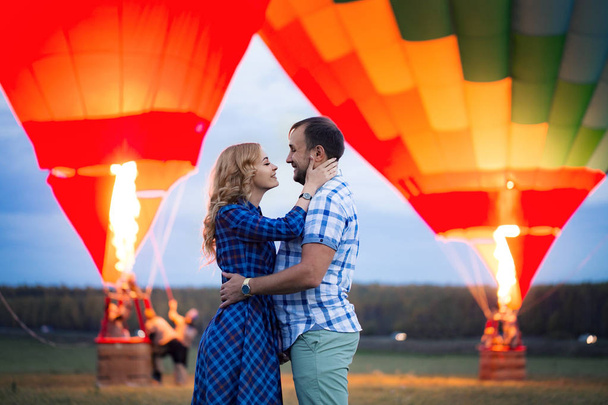 Hermosa pareja romántica abrazándose en el prado. globo de aire caliente sobre un fondo - Foto, Imagen