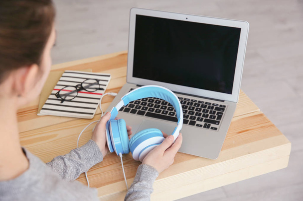 Audio book concept. Young woman using laptop with headphones, close up - Foto, imagen