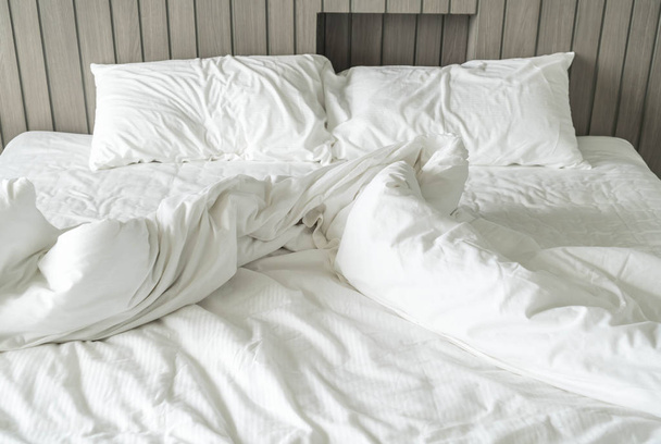 cama arrugada con decoración de almohada blanca desordenada en el dormitorio
  - Foto, imagen