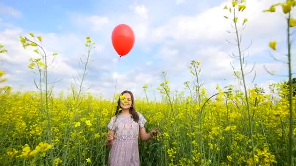 κορίτσι στέκεται στο πεδίο και απελευθερώνει μπαλόνια στον ουρανό - Πλάνα, βίντεο
