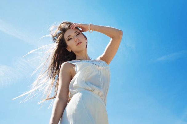 Young charming brunette woman on sea coast. Amazing view from the top. Portrait of young woman against clear sky - Foto, Imagem