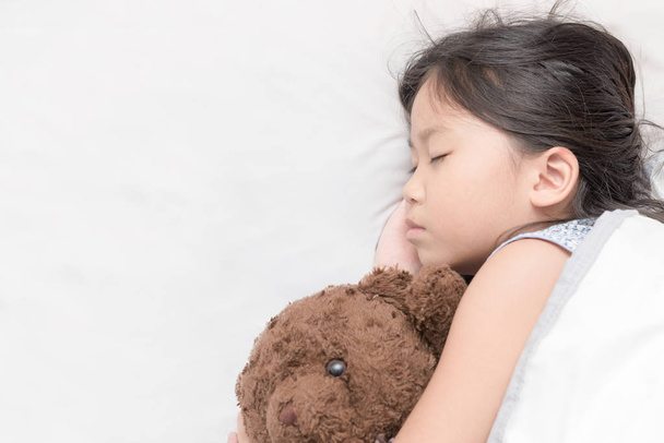 χαριτωμένο μικρό ασιατικό κορίτσι κοιμούνται και αγκαλιά αρκουδάκι  - Φωτογραφία, εικόνα
