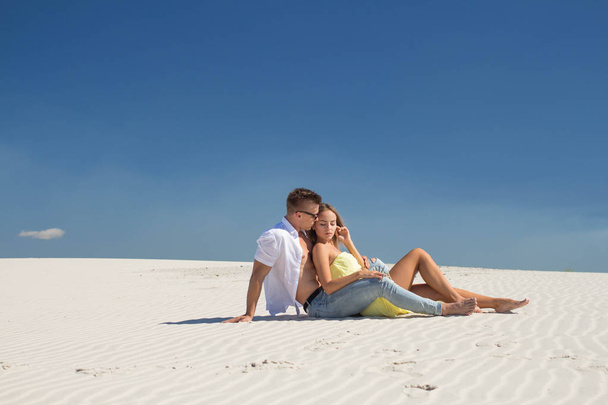A guy with a girl talking lying on white sand - Zdjęcie, obraz