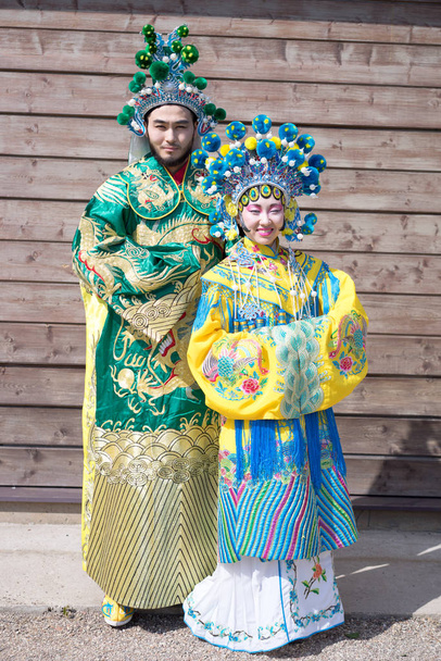 Chinesische Männer und Frauen in traditionellen Trachten stehen in der Nähe der Holzwand - Foto, Bild