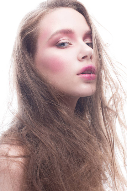 A young girl with loose long hair and bright creative makeup. Beautiful model with red lips and blush on a white isolated background. Pure shining skin - Φωτογραφία, εικόνα