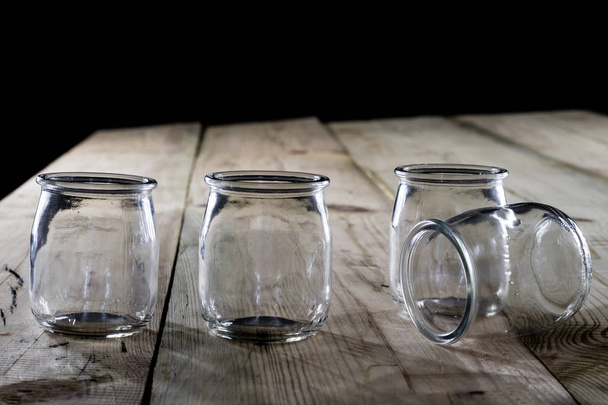 Empty jars on a wooden table, black background - Foto, immagini