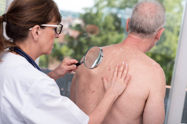 Dermatologist examining the skin of a patient - Photo, Image