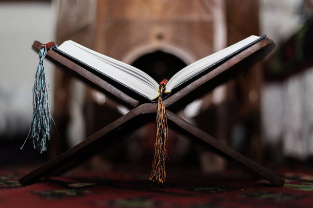 Libro Sagrado del Corán de los Musulmanes, un libro abierto en un stand con rosario
 - Foto, Imagen