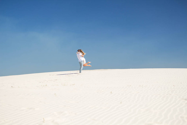 Emocional encuentro de amantes en una colina de arena blanca
 - Foto, Imagen