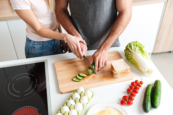 Loving couple standing at kitchen and cooking together - Photo, Image