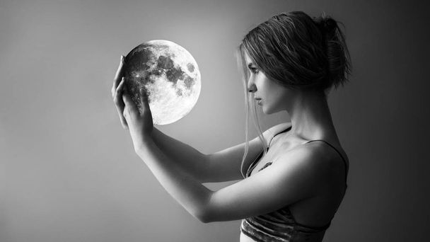 Hermosa chica sostiene la luna en sus manos
 - Foto, imagen