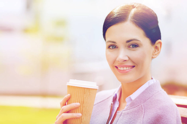 smiling woman drinking coffee outdoors - 写真・画像