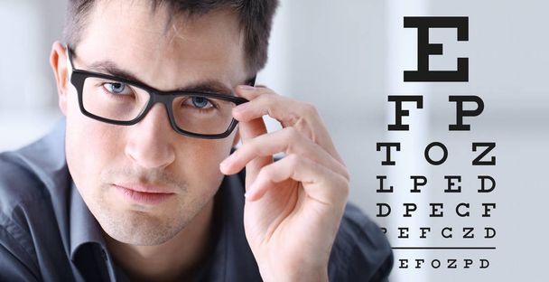мужское лицо с очками на фоне диаграммы зрения, офтальмологическая концепция исследования глаз
 - Фото, изображение