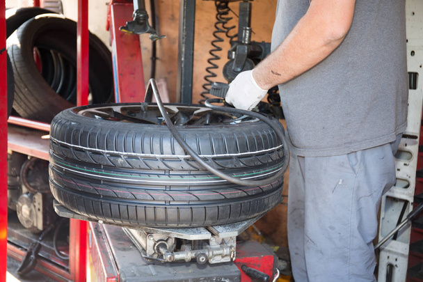 técnico especialista muda pneu do carro com sua máquina
 - Foto, Imagem