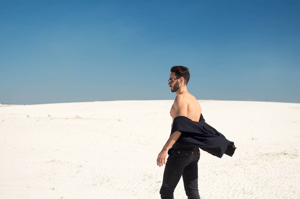 El tipo está girando con el viento en su camisa en el desierto
 - Foto, Imagen