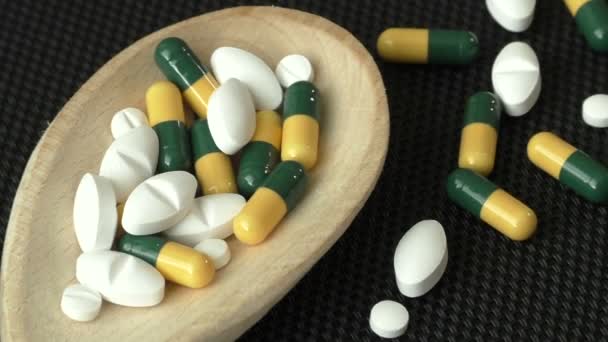 Assorted pharmaceutical medicine pills, tablets and capsules on wooden spoon - Footage, Video