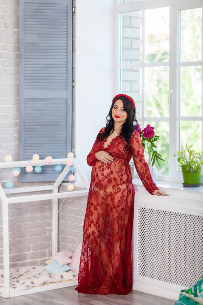 zwangere vrouw in het rood thuis - Foto, afbeelding