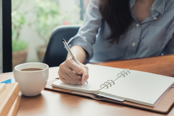 Close-up de jovem bela mulher escrevendo em notebook enquanto sentado
 - Foto, Imagem