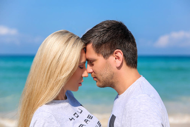Outdoor closeup portrait of pretty young couple in love having fun in hot weather and feeling happy together on the tropical island. Posing and hugs alone on the beach. - Photo, Image