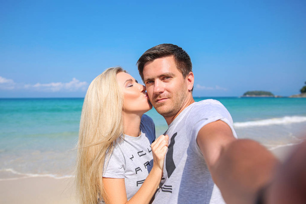 Buiten close-up portret van mooie jonge verliefde paar neemt een zelf-ie plezier bij warm weer en het gevoel gelukkig samen op het tropische eiland. Poseren en knuffels alleen op het strand. - Foto, afbeelding