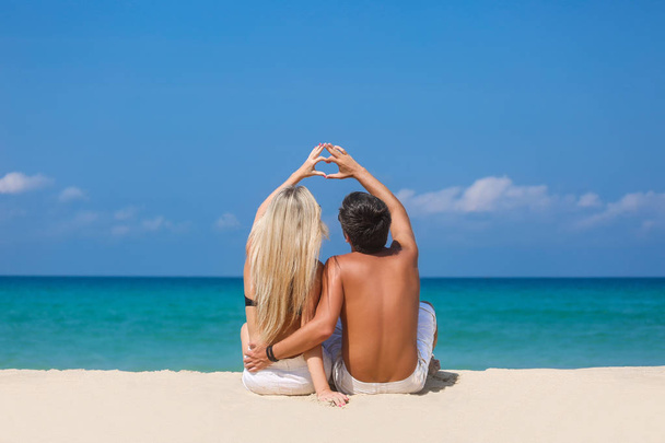 Pareja romántica sentada en la playa y disfrutando de hermosas vistas al mar, vista lateral, pasar tiempo juntos, concepto de vacaciones de verano
 - Foto, Imagen