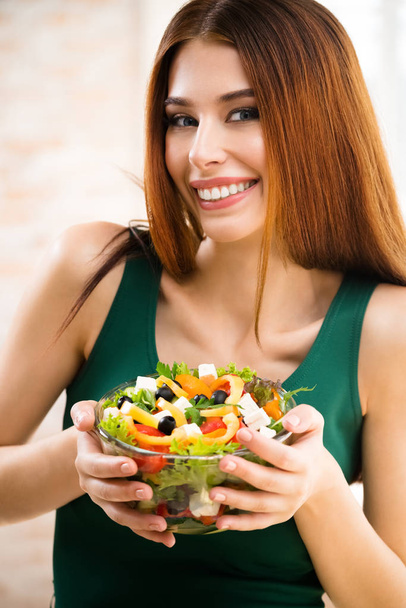 Beautiful young woman eating salad, indoor - Zdjęcie, obraz