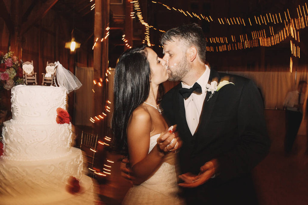 El novio besa la cara de la novia cubierta con glaseado de pastel de boda
 - Foto, Imagen