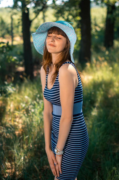 帽子の幸せな若い女の子が夏の日に公園を散歩します。 - 写真・画像