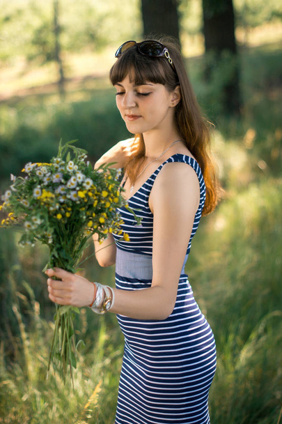 Красива дівчина з букетом з польових квітів на природі
. - Фото, зображення