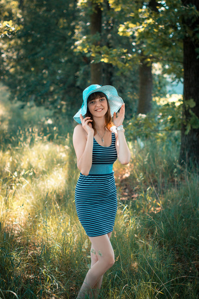 Happy young girl in a hat walks in the park in the summer day. - Zdjęcie, obraz
