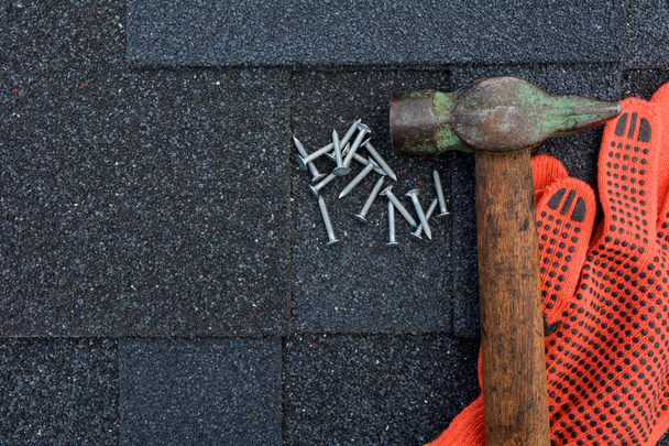 Close-up op asfalt dakbedekking Shingles achtergrond. Dakshingles - dakpannen. Asfalt dakshingles hamer, handschoenen en nagels - Foto, afbeelding