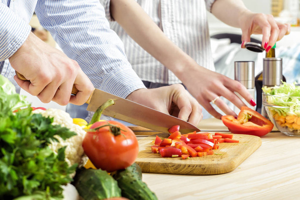 Ręce człowieka posiekana czerwona papryka na pokładzie. Para do krojenia warzyw w kuchni - Zdjęcie, obraz