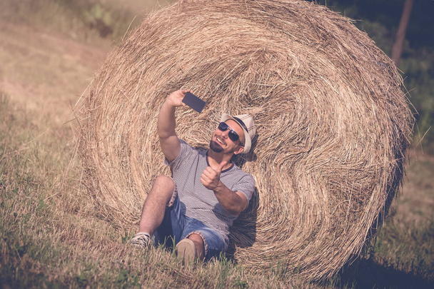 Man taking selfie with smartphone on the meadow  - Foto, Bild